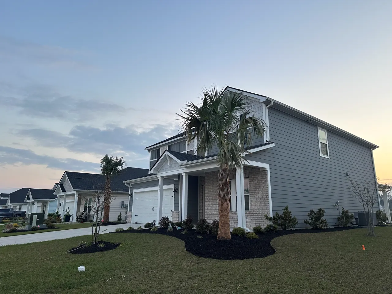 Home exterior at dusk with fresh mulch beds and a clean-cut lawn.