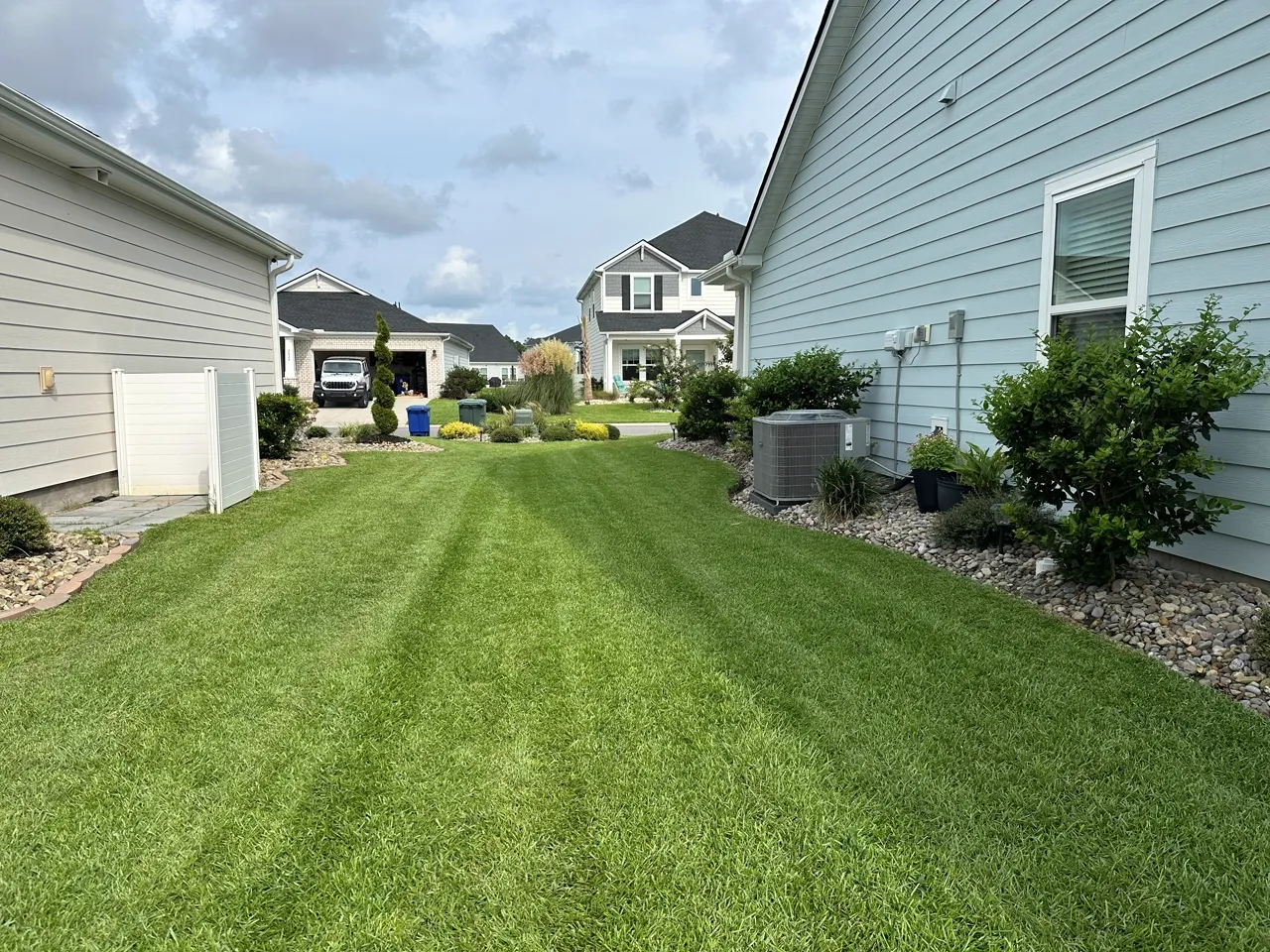 Striped side yard, clean-cut edge along the house and a rock border bed.