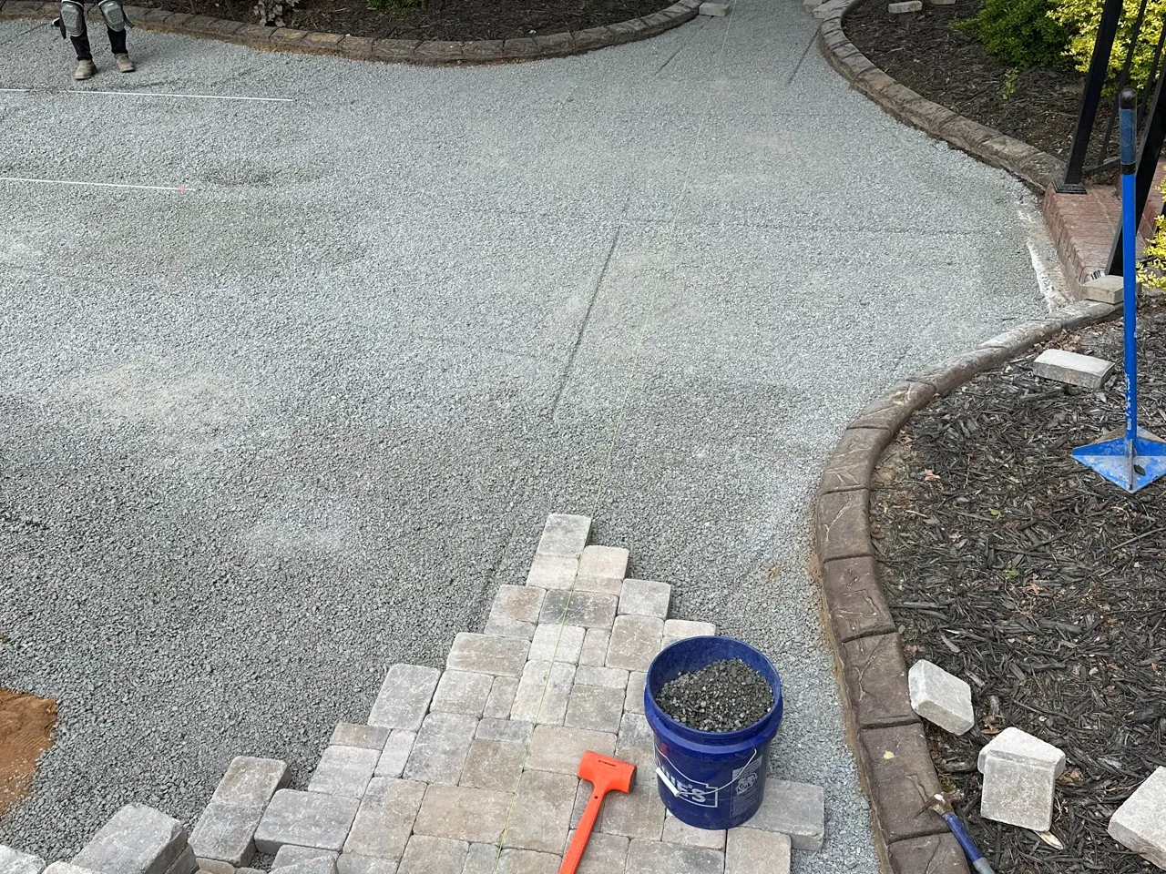 Paver walkway base being cut and set into a curved gravel bed.