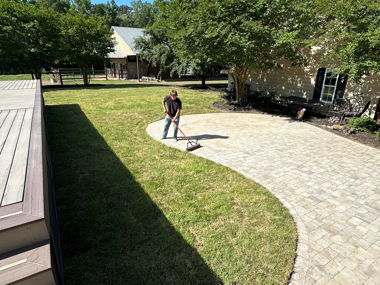Curved paver walkway with steps down to a lawn, crew sweeping the joints.